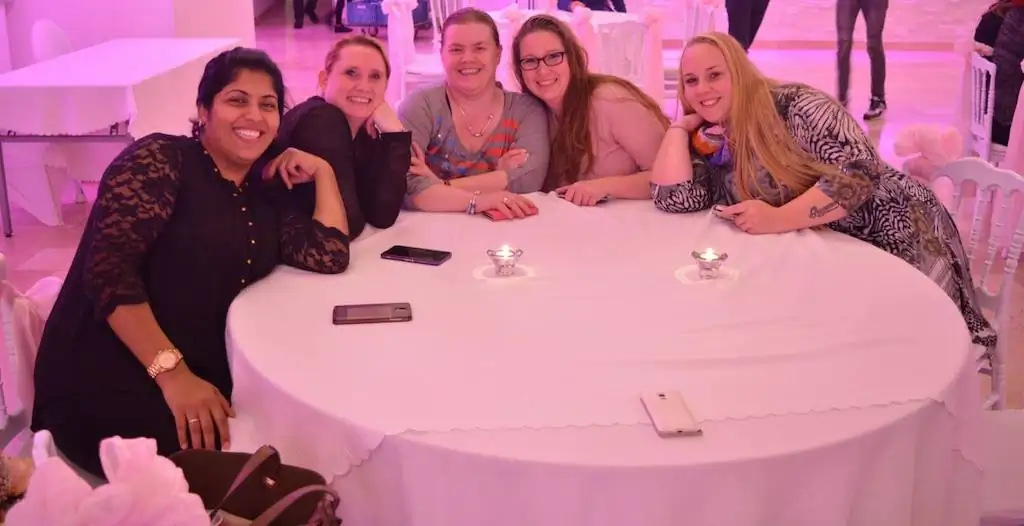 Groep blije kraamverzorgsters van Kraamzorg Mama genieten van elkaars gezelschap en vieren samen het eindejaarsfeest.