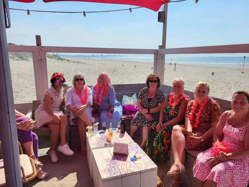 Groep kraamverzorgsters van Kraamzorg Mama geniet van het zonnige weer tijdens een mama-dag evenement bij een sfeervolle straattent.