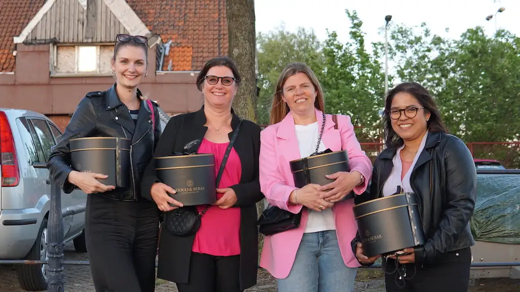 Vier vrolijke kraamverzorgsters van Kraamzorg Mama houden een cadeau vast tijdens het bedrijfsfeest