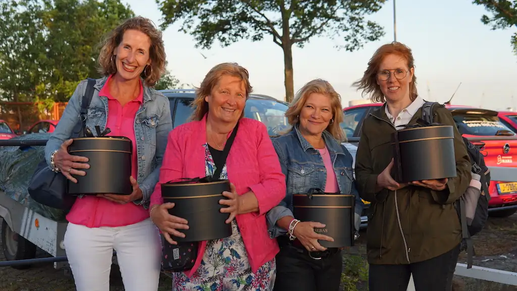 Vier vrolijke kraamverzorgsters van Kraamzorg Mama houden een cadeau vast tijdens het bedrijfsfeest