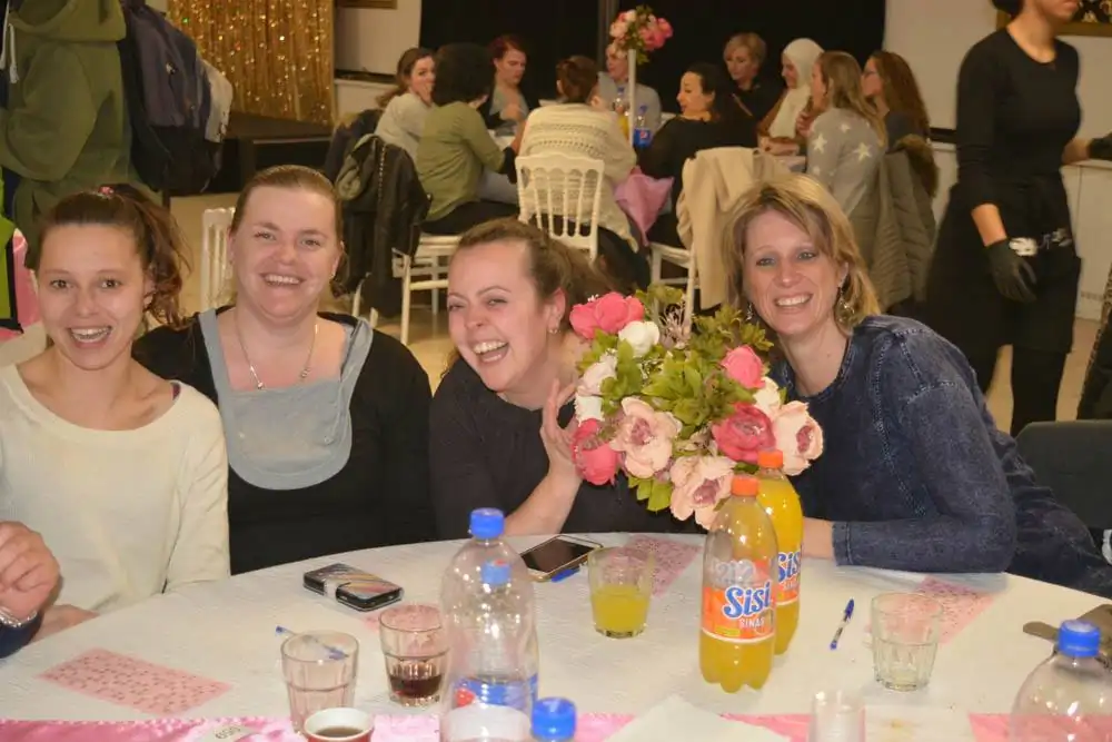 Groep blije kraamverzorgsters van Kraamzorg Mama genieten van elkaars gezelschap en vieren samen het eindejaarsfeest.
